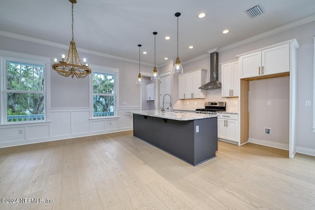 kitchen with white cabinetry, stainless steel range oven, wall chimney range hood, and a wealth of natural light