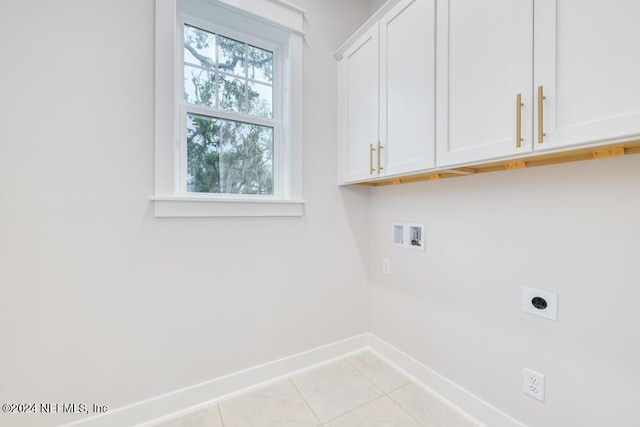 clothes washing area with electric dryer hookup, hookup for a washing machine, light tile patterned floors, and cabinets