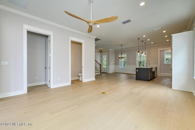 unfurnished living room featuring light hardwood / wood-style flooring, ceiling fan, ornamental molding, and sink