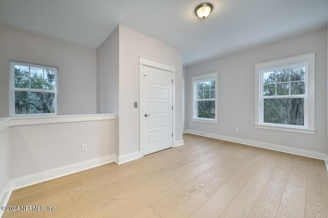 unfurnished bedroom featuring multiple windows, a closet, and light wood-type flooring