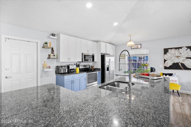 kitchen featuring appliances with stainless steel finishes, dark stone counters, white cabinetry, and light hardwood / wood-style floors