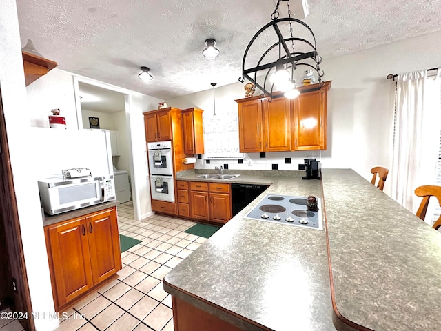 kitchen with white appliances, a textured ceiling, decorative light fixtures, and sink