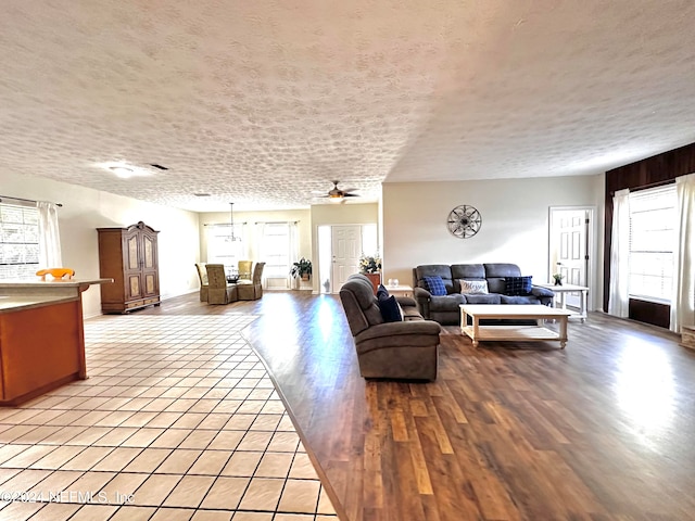 living room featuring a textured ceiling, light wood-type flooring, and ceiling fan