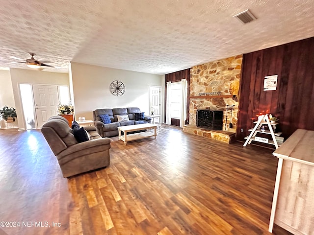 living room featuring a textured ceiling, a fireplace, hardwood / wood-style flooring, and ceiling fan