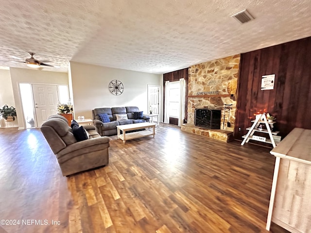 5609 County Road 352, Keystone Heights, FL 32656 - living room featuring wood finished floors, a textured ceiling, wood walls, a ceiling fan, and a fireplace