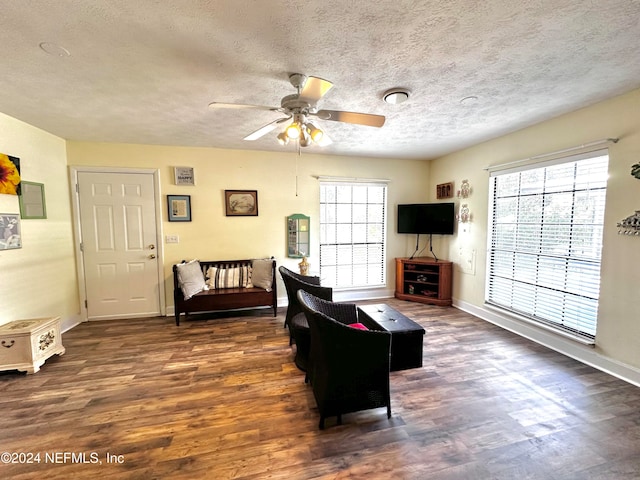 living room with a textured ceiling, a healthy amount of sunlight, dark wood-type flooring, and ceiling fan