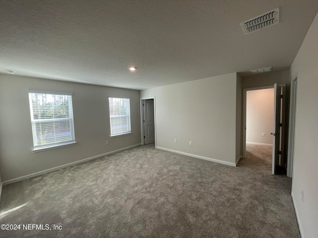 unfurnished room featuring carpet and a textured ceiling