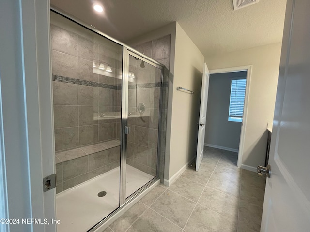 bathroom with a textured ceiling, tile patterned floors, and walk in shower