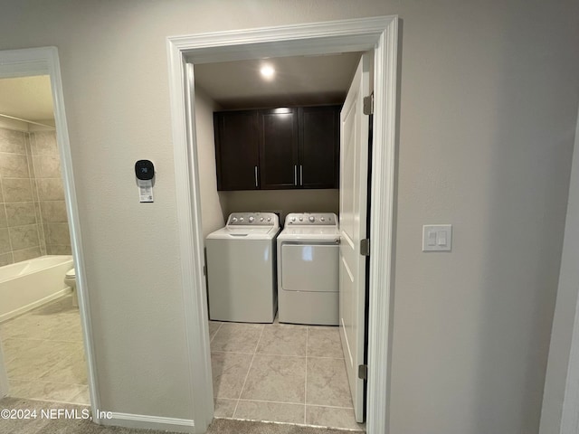 laundry area with washer and dryer, light tile patterned floors, and cabinets