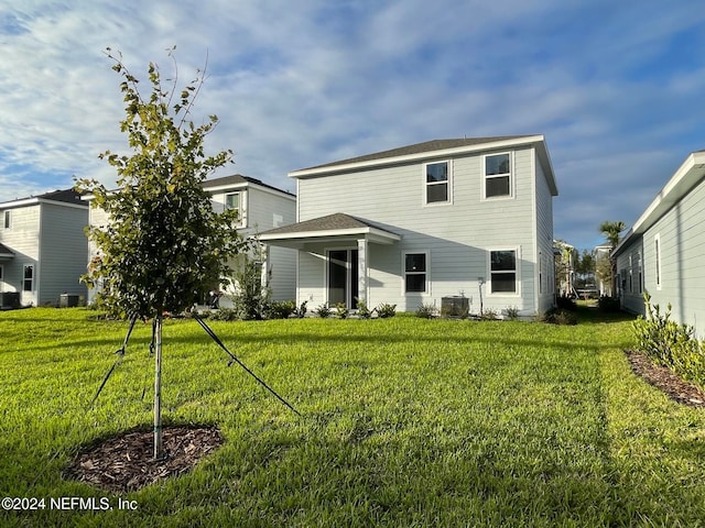 rear view of property featuring a lawn and cooling unit