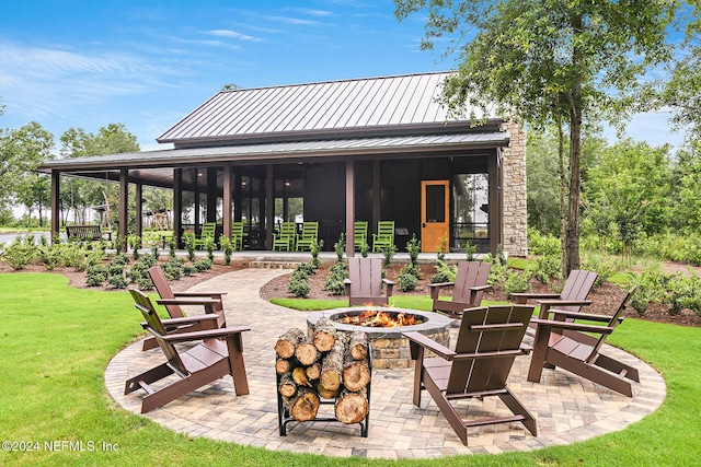 view of patio featuring a sunroom and an outdoor fire pit