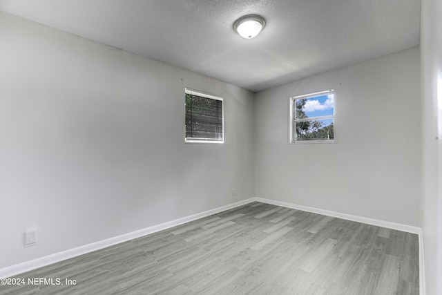 spare room featuring a textured ceiling and light hardwood / wood-style floors