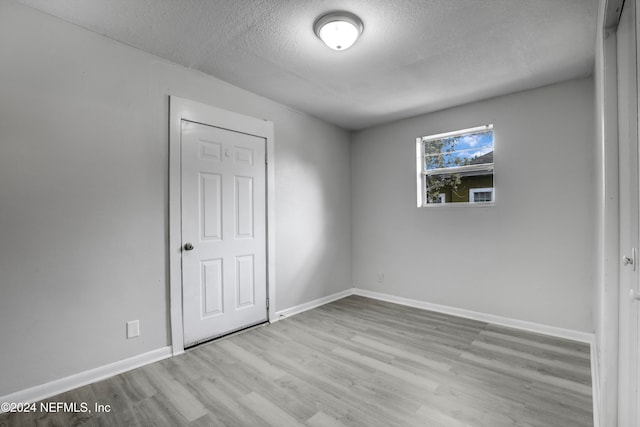 spare room featuring a textured ceiling and light hardwood / wood-style flooring