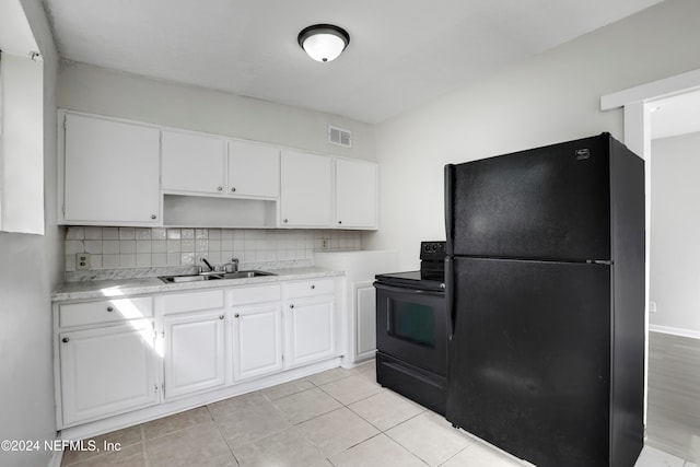 kitchen featuring decorative backsplash, light tile patterned floors, white cabinetry, black appliances, and sink