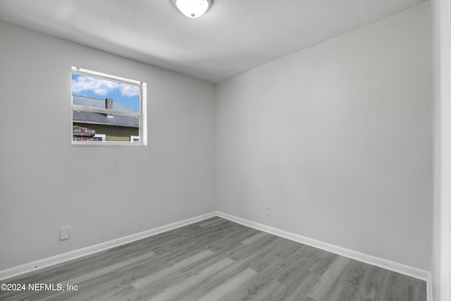 empty room featuring a textured ceiling and hardwood / wood-style floors