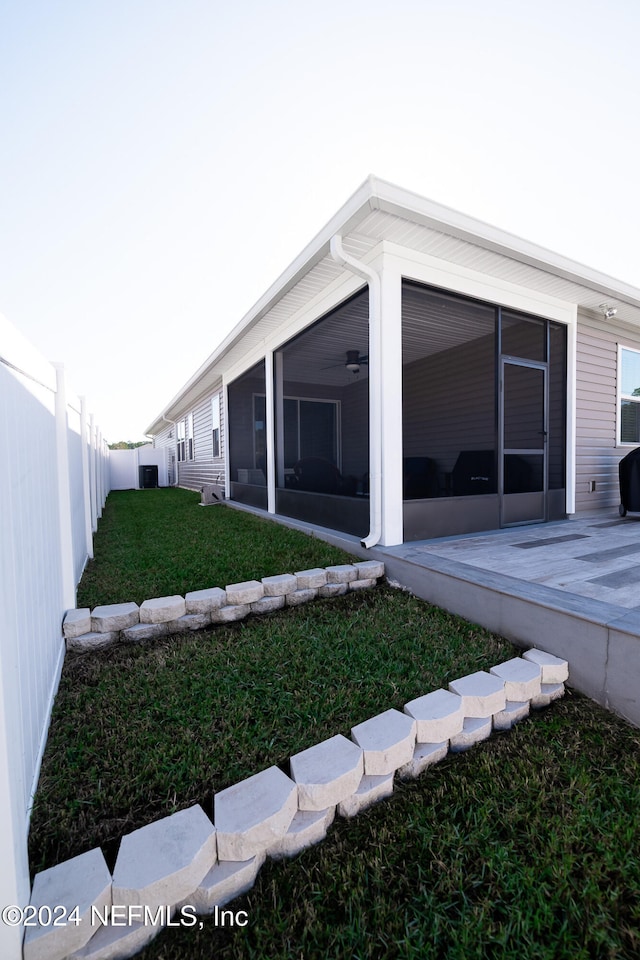 view of side of home with a lawn and a sunroom