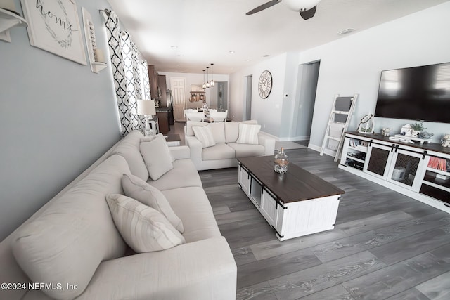 living room featuring dark wood-type flooring and ceiling fan with notable chandelier