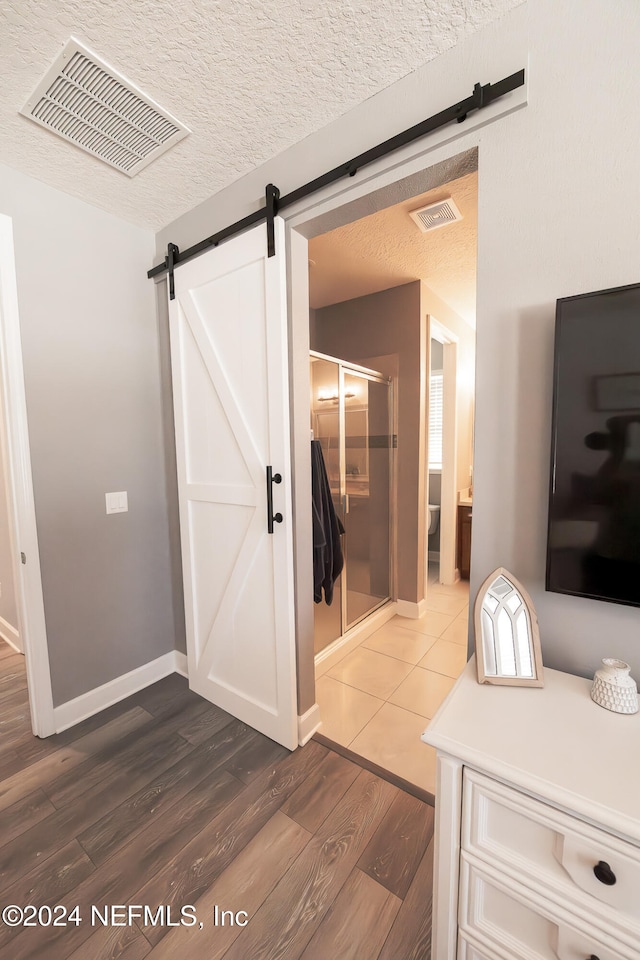 bathroom with hardwood / wood-style floors, a textured ceiling, and an enclosed shower