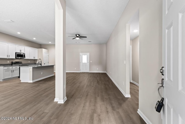 unfurnished living room with ceiling fan, a textured ceiling, and hardwood / wood-style floors