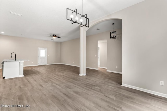 unfurnished living room featuring hardwood / wood-style flooring, sink, and ceiling fan