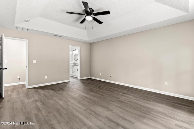 interior space with a raised ceiling, a textured ceiling, and dark hardwood / wood-style flooring