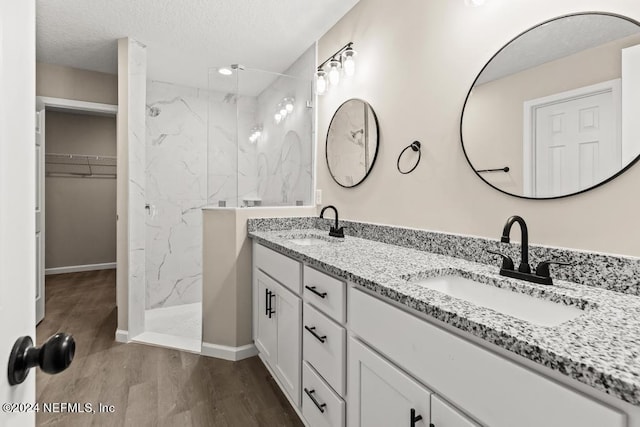 bathroom featuring a tile shower, hardwood / wood-style floors, vanity, and a textured ceiling