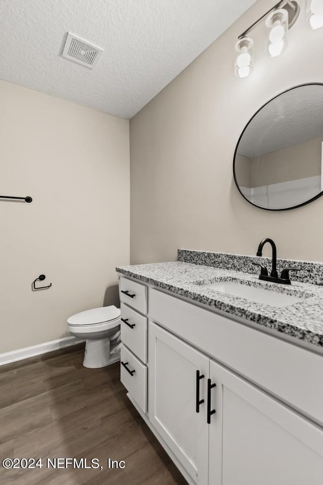 bathroom with vanity, hardwood / wood-style floors, a textured ceiling, and toilet