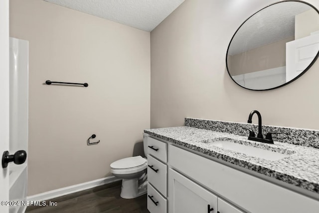 bathroom featuring vanity, toilet, wood-type flooring, and a textured ceiling