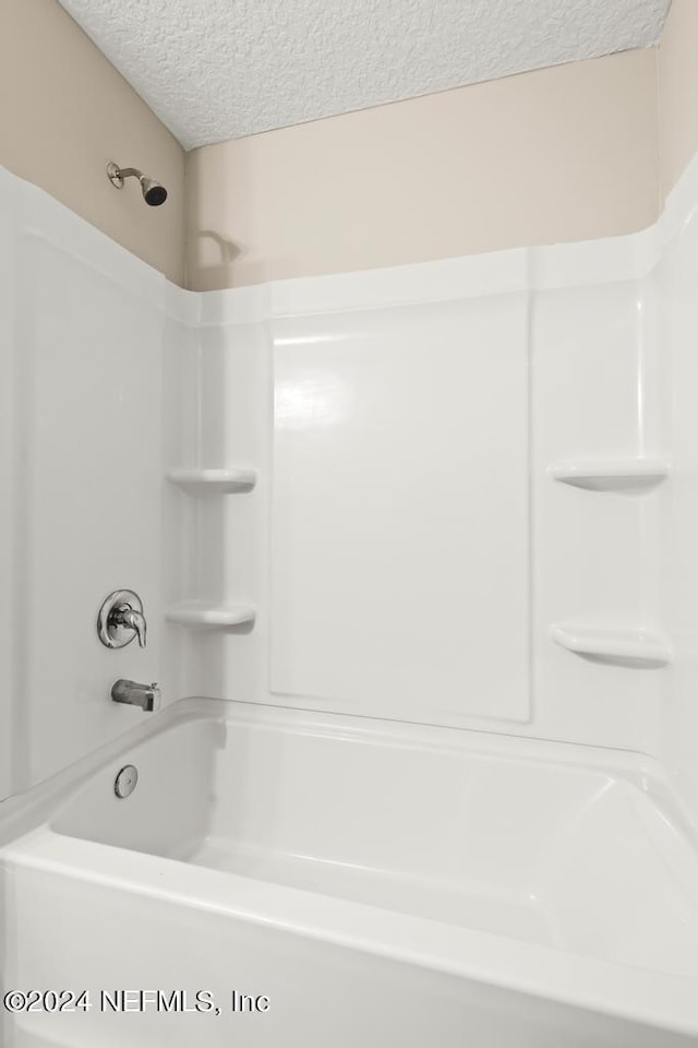 bathroom with a textured ceiling and washtub / shower combination