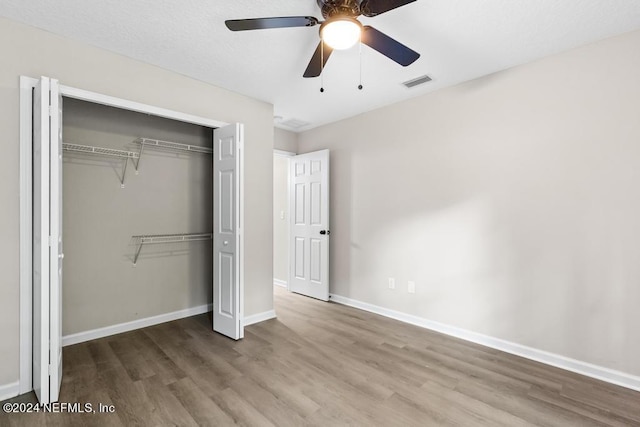 unfurnished bedroom with a closet, hardwood / wood-style floors, and ceiling fan