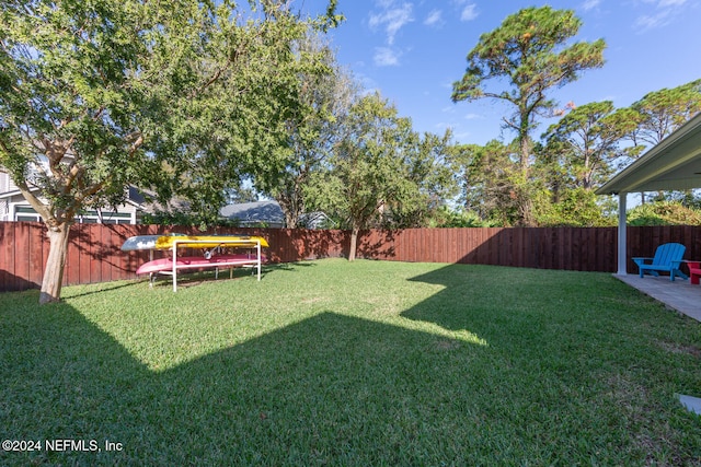 view of yard with a trampoline and a fenced backyard