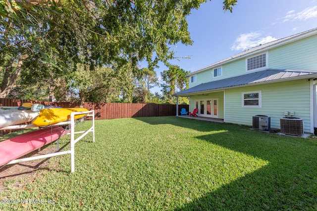 view of yard with central air condition unit, french doors, and a fenced backyard