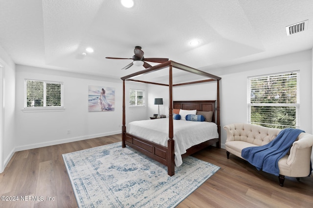 bedroom with wood finished floors, multiple windows, and a textured ceiling