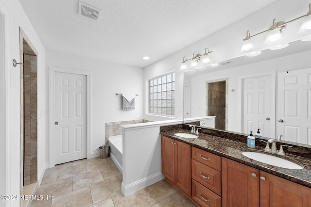 full bathroom with double vanity, visible vents, a sink, a textured ceiling, and a garden tub