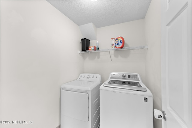 clothes washing area with washing machine and clothes dryer, laundry area, and a textured ceiling