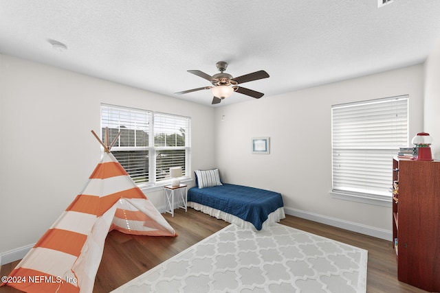 bedroom with ceiling fan, a textured ceiling, baseboards, and wood finished floors