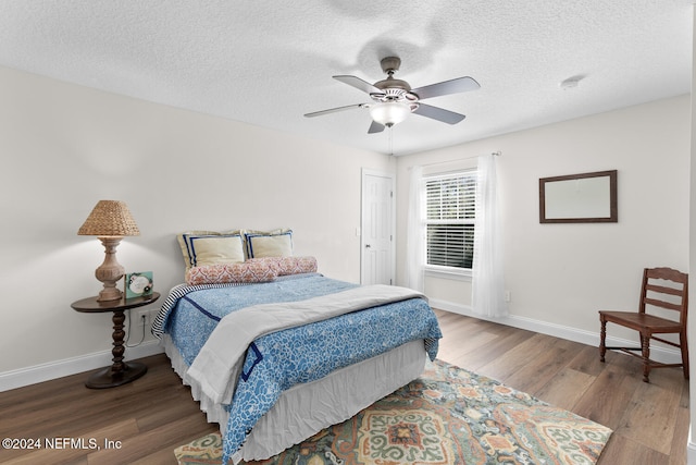 bedroom with baseboards, ceiling fan, wood finished floors, and a textured ceiling