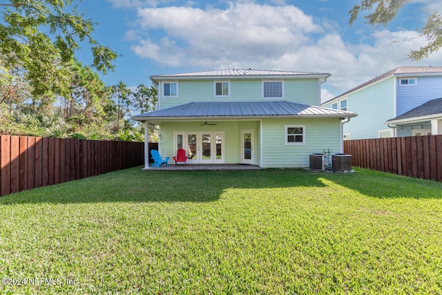 rear view of house with a ceiling fan, a lawn, central air condition unit, metal roof, and a fenced backyard