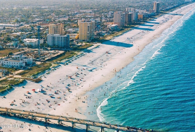 drone / aerial view featuring a view of city, a water view, and a beach view