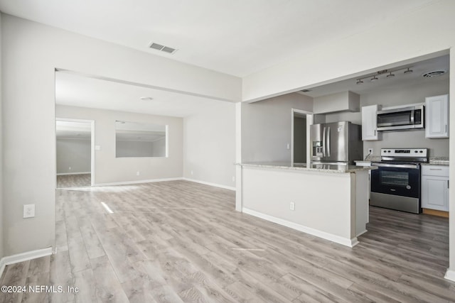 kitchen with white cabinetry, appliances with stainless steel finishes, light stone counters, and light hardwood / wood-style flooring