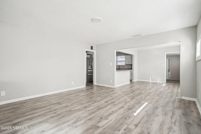 unfurnished living room featuring a wealth of natural light and light hardwood / wood-style flooring