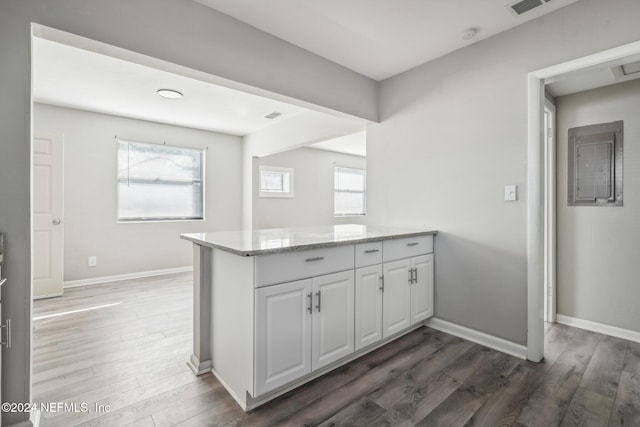 kitchen with white cabinets, a wealth of natural light, dark wood-type flooring, and light stone countertops