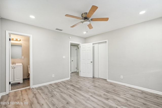 unfurnished bedroom featuring sink, ensuite bathroom, ceiling fan, a closet, and light wood-type flooring