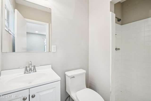 bathroom with vanity, toilet, and tiled shower