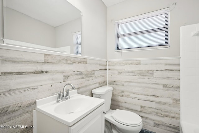 bathroom with toilet, vanity, and tile walls