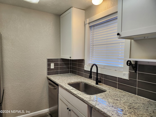 kitchen featuring white cabinetry, dishwasher, sink, and backsplash