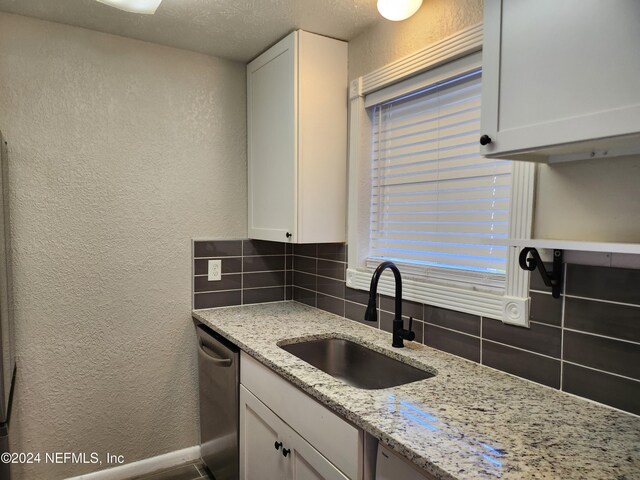 4836 Atlantic Blvd Unit 106, Jacksonville, FL 32207 - kitchen with a textured wall, dishwasher, decorative backsplash, white cabinets, and light stone counters