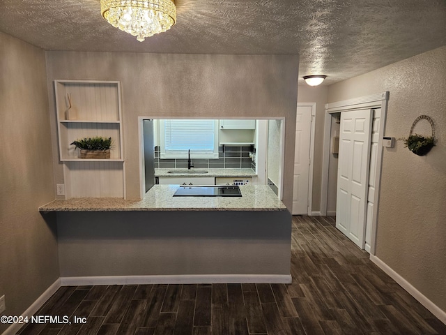 kitchen with light stone counters, a textured ceiling, black electric cooktop, and dark hardwood / wood-style floors