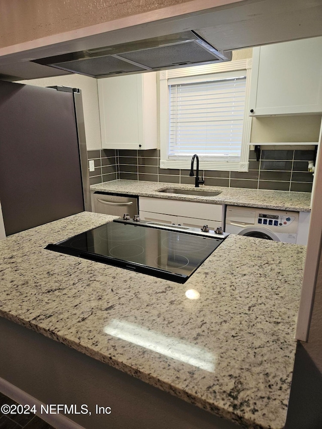 kitchen with white cabinetry, backsplash, washer / dryer, and sink