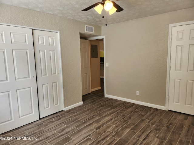 unfurnished bedroom with electric panel, ceiling fan, dark hardwood / wood-style flooring, a textured ceiling, and a closet